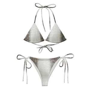 Może przedstawiać: Dwuczęściowy zestaw bikini z wzorem imitującym skórę gada w odcieniach bieli, szarości i brązu. Góra to model typu halter z trójkątnymi miseczkami, a dół to klasyczny krój z wiązaniami po bokach.