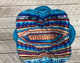May include: A blue and brown quilted bowl cozy with a geometric pattern. The cozy is made of fabric and has a quilted design.