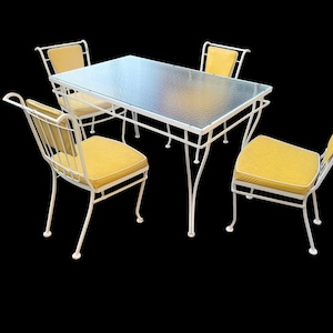 May include: White metal patio table set with four chairs. The table has a glass top and the chairs have yellow cushions.