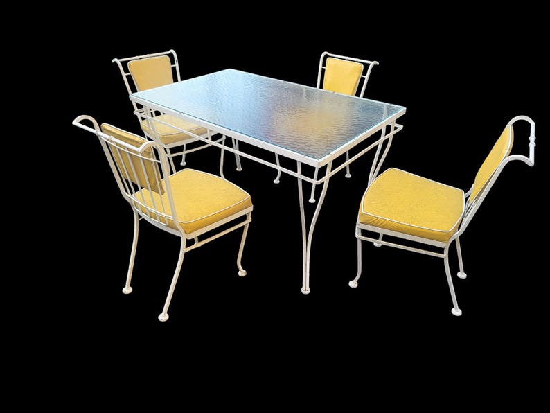 May include: White metal patio table set with four chairs. The table has a glass top and the chairs have yellow cushions.