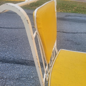 May include: White metal patio chair with a yellow padded seat and back. The chair has a simple, classic design.