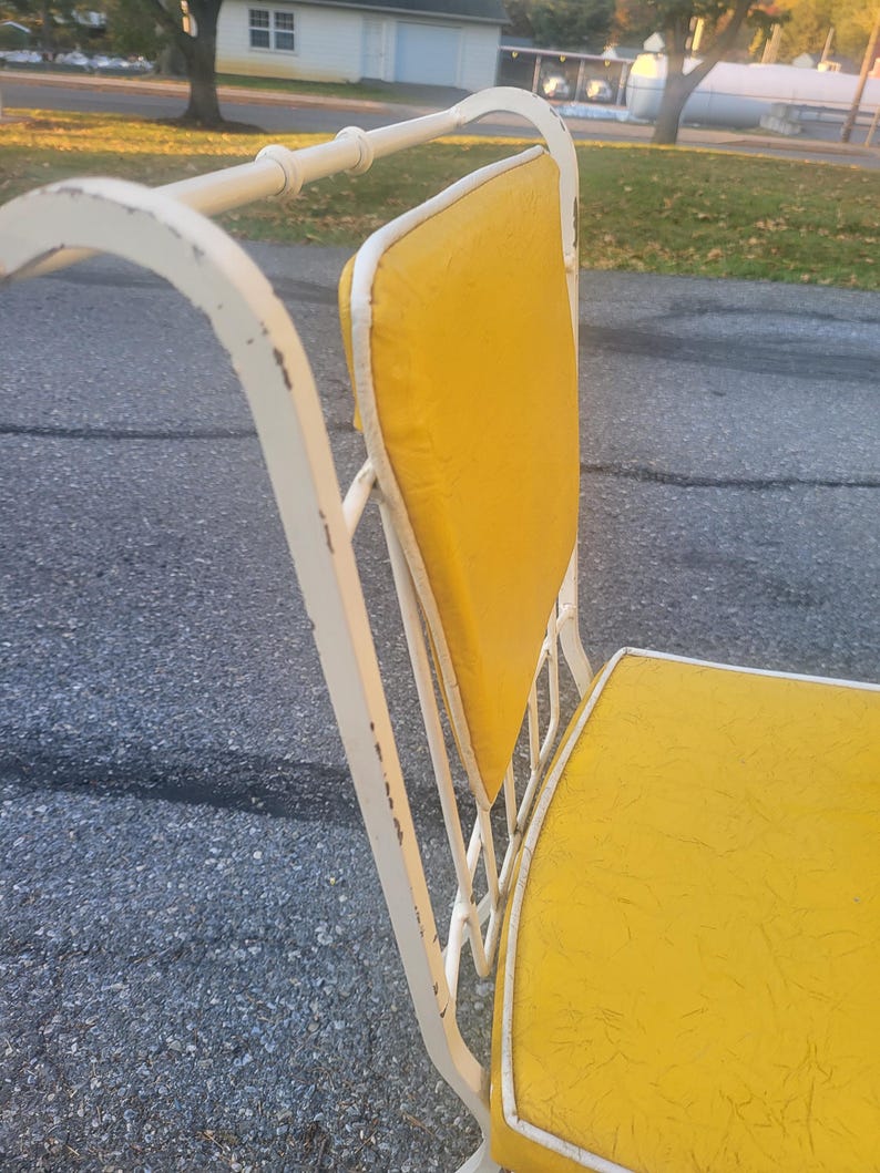 May include: White metal patio chair with a yellow padded seat and back. The chair has a simple, classic design.