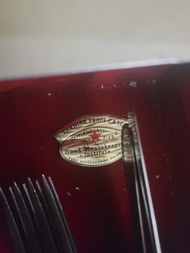 May include: A gold sticker with the text "Tarnish Proof Case" and "Tested and Approved" with a red star and the number "2149". The sticker also says "Good Housekeeping Institute" and "Good Housekeeping Magazine".
