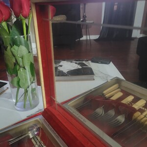 May include: A red velvet lined wooden box with a glass top, containing a set of silver Community Plate silverware. The box has the words "Community Plate" and "Stainless Steel" printed on the inside.