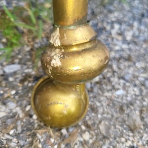 Op de afbeelding: Close-up van een messing meubelwiel met een afgeronde basis en een klein wiel. Het wiel heeft een gouden afwerking en het woord "Shepherd" is aan de zijkant gegraveerd. Het wiel is bevestigd aan een messing poot.