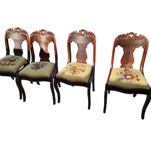 May include: Four antique wooden chairs with carved backs and floral patterned upholstery. The chairs have a dark brown finish and are in good condition.