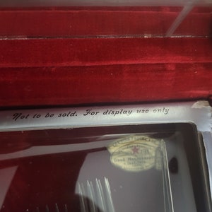 May include: A close-up of a silver box with a red velvet interior. The box contains a set of silver forks and a label that reads "Not to be sold. For display use only." The label also has a Good Housekeeping seal.