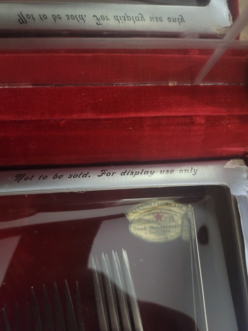 May include: A close-up of a silver box with a red velvet interior. The box contains a set of silver forks and a label that reads "Not to be sold. For display use only." The label also has a Good Housekeeping seal.