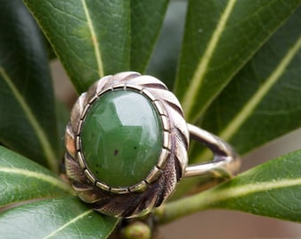 May include: A silver ring with a green jade stone set in a detailed silver setting.