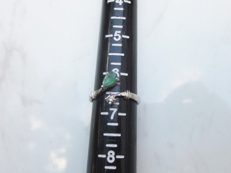 Puede incluir: Un anillo de plata con una piedra preciosa verde y un diamante m&aacute;s peque&ntilde;o. El anillo se muestra junto a una regla, con la piedra preciosa midiendo aproximadamente 6 mm de di&aacute;metro.