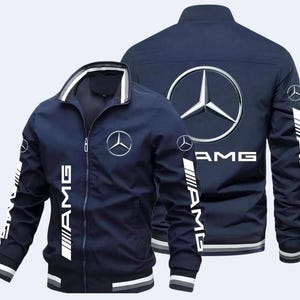 Könnte beinhalten: Marineblaue Reißverschlussjacke mit weißen Akzenten und dem AMG-Logo. Die Jacke zeigt das Mercedes-Benz-Logo auf der Vorder- und Rückseite, mit AMG-Branding auf den Ärmeln. Ein sportliches, lässiges Oberbekleidungsstück.