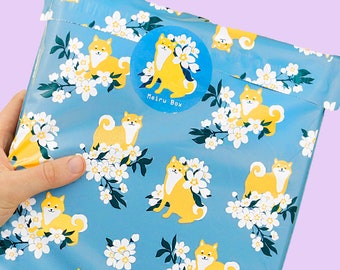 May include: A blue and white patterned poly mailer with a sticker that says "Petru Box" and a picture of a Shiba Inu dog.