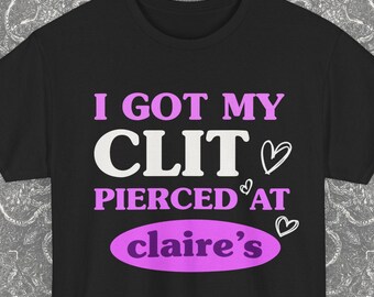 May include: Black t-shirt with the text "I GOT MY CLIT PIERCED AT claire's" in white and pink lettering. The text is arranged in a stacked format, with a heart symbol next to the word "CLIT" and another next to "claire's".