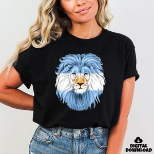 May include: Black t-shirt featuring a lion's head with a mane designed in the colors of the Argentinian flag: light blue and white. The lion's face is detailed with yellow and brown tones. The words "DIGITAL DOWNLOAD" are in the bottom right corner.