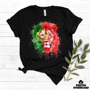 Könnte beinhalten: Schwarzes T-Shirt mit einem Aquarelldesign eines Löwenkopfes und der portugiesischen Flagge. Der Löwe ist rot und die Flagge ist grün und rot. Das Design hat einen Spritzeffekt. Die Worte "DIGITALER DOWNLOAD" stehen unten rechts.