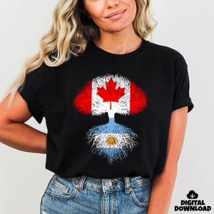May include: Black t-shirt featuring a tree design with the Canadian flag as the crown and the Argentinian flag as the roots. The shirt has a digital download icon in the bottom right corner.