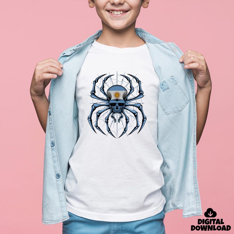 May include: White t-shirt featuring a detailed graphic of a spider skull with the Argentinian flag on its head. The spider is black and blue, set against a web design. The shirt is worn by a person wearing a light blue denim shirt.
