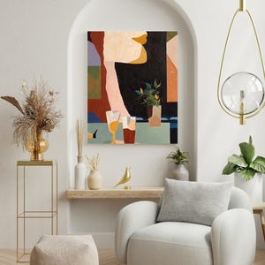 以下が含まれることがあります： 人物と2つのグラスの飲み物が描かれた抽象画。 アートワークは、明るい色の木製棚の上にあるアーチ型のアルコーブに展示されています。 金色の鳥の像と白いアームチェアが前景にあります。