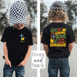 May include: Black t-shirt with a cross and lemon graphic, the name "Clark" is below the cross. The back of the shirt has the text "Life gave me some lemons but my Jesus he be makin' lemonade" with lemon graphics.