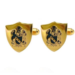 K&ouml;nnte beinhalten: Ein Paar goldfarbene Manschettenkn&ouml;pfe mit Schilddesign. Jeder Manschettenknopf zeigt ein Wappen mit einem blau-schwarzen Emblem und dem Schriftzug "Harvey". Die Manschettenkn&ouml;pfe haben eine polierte Oberfl&auml;che.