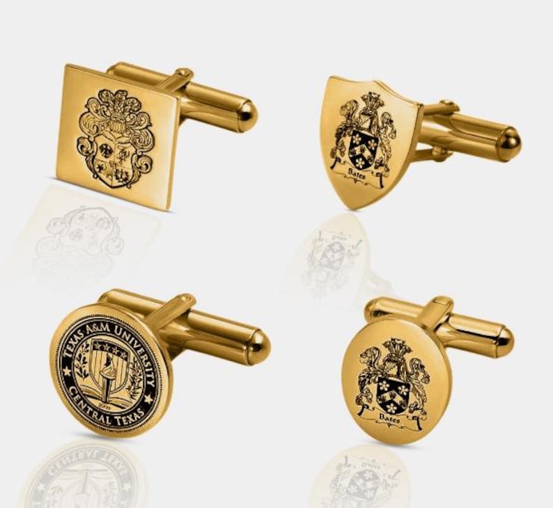 K&ouml;nnte beinhalten: Vier goldfarbene Manschettenkn&ouml;pfe mit verschiedenen eingravierten Designs. Einer ist quadratisch mit Wappen, ein anderer schildf&ouml;rmig mit Wappen und dem Namen "Bates", und zwei sind rund mit Wappen und Text, einschlie&szlig;lich "Texas A&M University Central Texas".