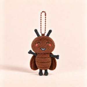 May include: A brown plush insect keychain featuring a round head with two antennae, a segmented body, and dark gray limbs. The character has a smiling face with white teeth and small pink cheeks, attached to a metallic copper-colored ball chain.