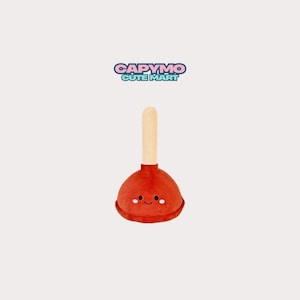 Op de afbeelding: Een pluche speelgoed in de vorm van een ontstopper met een rode zuignap en een lichtbruine houten steel. De rode zuignap heeft een klein geborduurd gezichtje met twee zwarte ogen, een gebogen mond en twee witte ronde wangen. De tekst CAPYMO CUTE MART staat erboven.