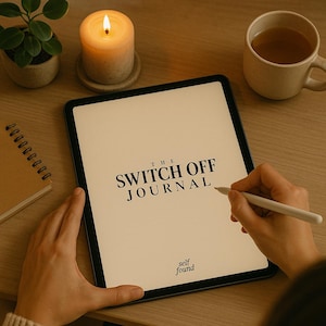 Könnte beinhalten: Ein Tablet-Computer zeigt den Text "THE SWITCH OFF JOURNAL" mit den Worten "self found" darunter an. Eine Person verwendet einen Stift, um auf den Bildschirm zu schreiben. Das Tablet liegt auf einem Holztisch mit einer brennenden Kerze und einer Tasse Tee.