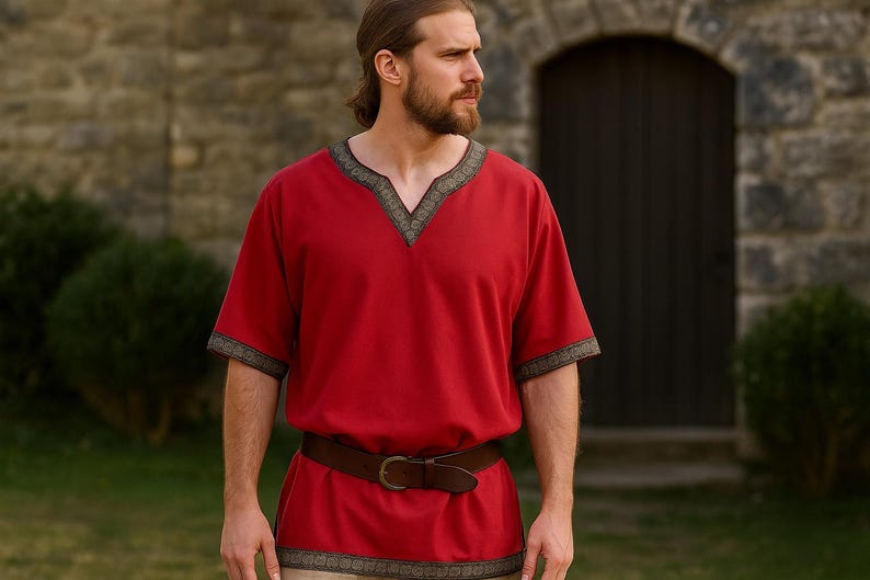 K&ouml;nnte beinhalten: Ein rotes T-Shirt mit V-Ausschnitt und kurzen &Auml;rmeln, verziert mit einer dekorativen Bord&uuml;re. Das T-Shirt wird mit einem braunen Lederg&uuml;rtel kombiniert. Das Kleidungsst&uuml;ck scheint aus einem weichen Stoff zu sein.