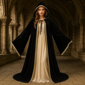 May include: A black hooded cloak with gold trim and a cream-colored dress. The cloak has wide sleeves and a long train. The outfit is worn in a stone corridor with arched ceilings and pillars, creating a medieval or fantasy theme.