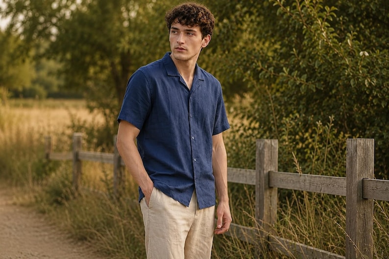 May include: A short-sleeved navy blue button-down shirt with a notched collar and a textured finish, paired with light beige trousers. The shirt features a straight hemline and a front button closure, providing a clean and simple look.