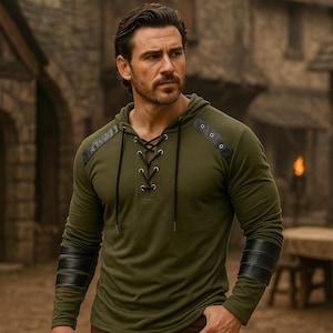 Könnte beinhalten: Olivgrünes Kapuzenshirt mit schwarzen Lederakzenten an Schultern und Ärmeln. Das Shirt hat einen Schnürhalsausschnitt und ist aus einem weichen, bequemen Material gefertigt. Es ist ein langärmliges Oberteil.