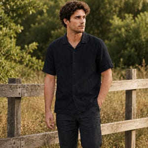 May include: A short-sleeved button-down shirt in a solid dark navy blue color featuring a classic collar, a front button placket, and a straight hemline, paired with matching dark navy blue trousers that have a simple, clean-cut design.