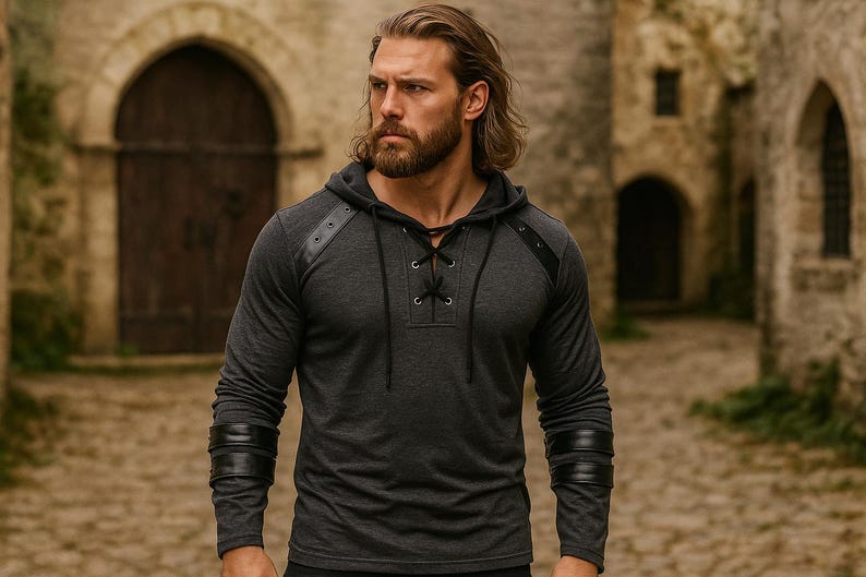 May include: Dark gray long-sleeve hooded shirt with leather accents on the shoulders and sleeves. The shirt features a lace-up neckline and is made of a soft, comfortable material. The shirt is a casual style.