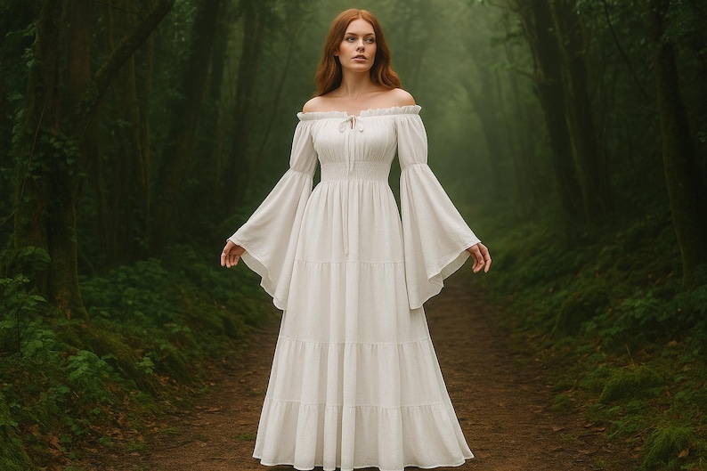Puede incluir: Un vestido blanco con hombros descubiertos, mangas largas acampanadas y una falda escalonada. El vestido tiene un corpi&ntilde;o ajustado y un dise&ntilde;o largo y fluido. El fondo es un exuberante bosque verde con un camino.