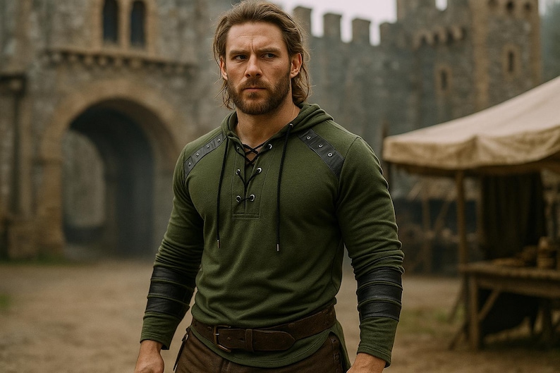 May include: An olive green hooded shirt with black leather accents on the shoulders and sleeves. The shirt features a lace-up neckline and is paired with a brown belt and pants. The background shows a stone building and a tent.