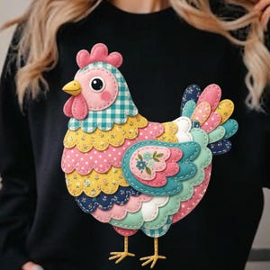 Puede incluir: Sudadera negra con un diseño de gallina colorida estilo patchwork. La gallina tiene una cresta y una barbilla rosas, un pico amarillo y un cuerpo hecho de varias telas estampadas, incluyendo lunares y estampados florales. El diseño está delineado en blanco.