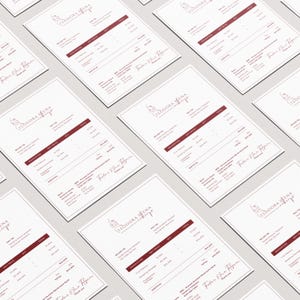 May include: Multiple white invoices with burgundy text and a logo that reads "TEODORA IENA makeup". The invoices include details such as "Wedding Package" and "Engagement Package". The invoices are arranged on a light gray surface.