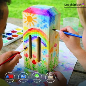 Puede incluir: Un proyecto de artesan&iacute;a rectangular de madera se pinta con acuarelas. La parte superior est&aacute; pintada con un arco&iacute;ris, un sol y nubes. Los lados presentan flores y vegetaci&oacute;n. El texto "Label Splash" es visible.