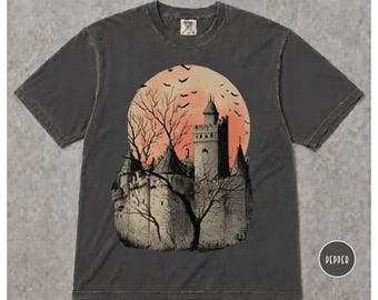 May include: A charcoal gray short-sleeve t-shirt featuring a graphic print of a stone castle with turrets, bare trees, and a large orange moon filled with flying bats. The word PEPPER is printed in a small white circle in the bottom right corner.