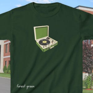 May include: Forest green t-shirt featuring a vintage-style illustration of a green record player with a black vinyl record. The record player is open, showcasing its details. The words "forest green" are printed at the bottom of the shirt.
