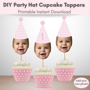 May include: Three cupcake toppers featuring a baby face cutout wearing a pink and white gingham party hat on a wooden stick, inserted into cupcakes with pink and white heart-patterned wrappers. Text reads: DIY Party Hat Cupcake Toppers Printable Instant Download.