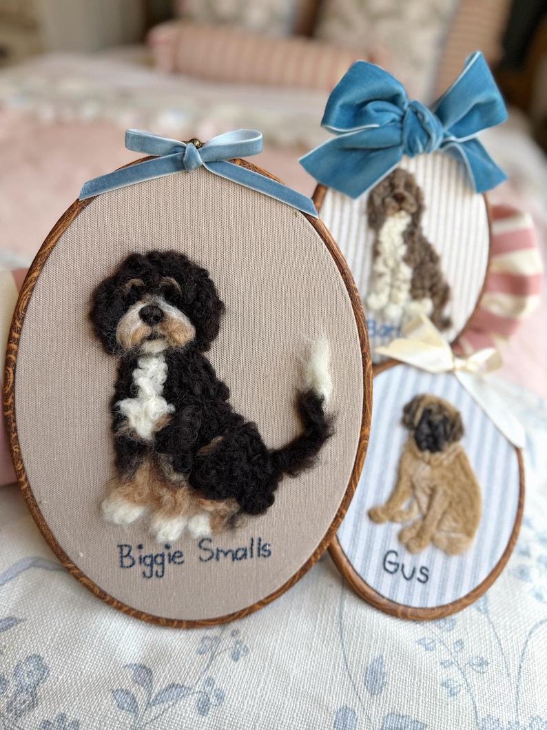 May include: Three oval embroidery hoops featuring needle-felted dog portraits. The largest hoop displays a black, white, and tan dog with the text Biggie Smalls. Two smaller hoops show a brown and white dog and a tan dog named Gus.