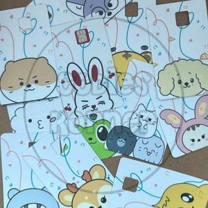 May include: A collection of white cards featuring cartoon animal faces, including a rabbit, dog, cat, and bear. Each card has a small square cutout and is decorated with hearts and the number "17". The cards are scattered.