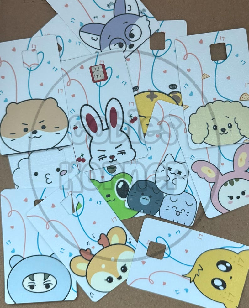 May include: A collection of white cards featuring cartoon animal faces, including a rabbit, dog, cat, and bear. Each card has a small square cutout and is decorated with hearts and the number "17". The cards are scattered.