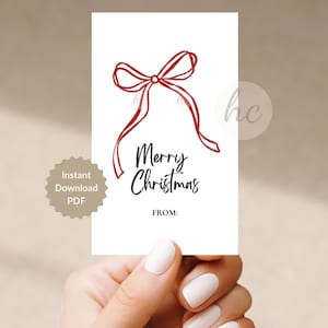 Könnte beinhalten: Ein rechteckiges weißes Geschenkanhänger-Kärtchen mit einer roten Strichzeichnung einer Schleife oben. Unter der Schleife steht der Text Merry Christmas in einer schwarzen Schreibschrift, gefolgt von dem Wort FROM: in einer einfachen schwarzen Schrift.