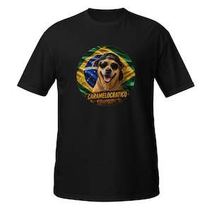 Może przedstawiać: Czarny t-shirt z okrągłą grafiką przedstawiającą brązowego psa w okularach przeciwsłonecznych, czarnej czapce z daszkiem i złotym łańcuchu. Pies znajduje się na tle brazylijskiej flagi, z napisem CARAMELOCRATICO wydrukowanym na żółto pod psem.