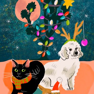 May include: A black cat wearing a red and black scarf sits next to a white dog wearing reindeer antlers and a red and white Santa hat. A small lizard wearing a Santa hat is in front of them. A Joshua tree with colourful lights is in the background.