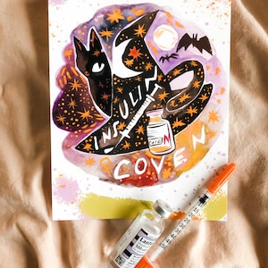 May include: A watercolor illustration of a black cat wearing a witch's hat with the words "Insulin Coven" written in a whimsical font. The illustration is surrounded by stars and bats. A vial of insulin and a syringe are also depicted in the image.