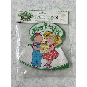 Op de afbeelding: Een verpakking van zes Cabbage Patch Kids feesthoeden. De hoeden zijn wit met rood-witte strepen. De hoeden hebben een cartoonafbeelding van een jongen en een meisje die een cadeau vasthouden. De verpakking heeft de woorden "Party Hats" en "Cabbage Patch Kids".